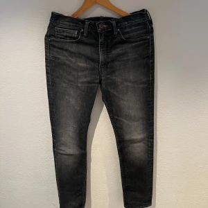 Svarta Levis 511 jeans - Säljer ett par svarta Levis 511 jeans i slim fit. De har en klassisk femficksdesign och är tillverkade i en bomullsblandning för extra komfort. Perfekta för en stilren look.