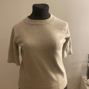 Beige tröja med trekvartsärm - Snygg beige tröja med trekvartsärm och rund halsringning. Perfekt för en stilren och enkel look. Passar bra till både jeans och kjol.