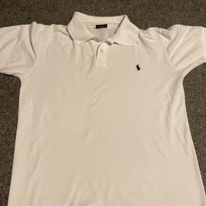 Vit pikétröja från Polo Sport Ralph lauren - Säljer en klassisk vit pikétröja från Polo Sport Ralph Lauren. Tröjan är tillverkad i 100% bomull och har en broderad logotyp på bröstet. Den har små fläckar som knappt syns när man har på sig den! Den är i storlek L men kan vara liten i storleken. Tveka inte att höra av er!☀️