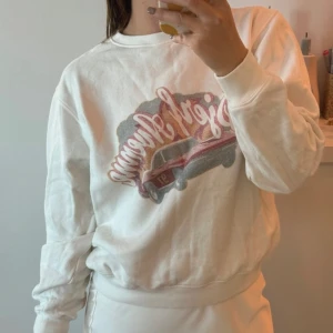 Vit sweatshirt från Djerf Avenue - Säljer en vit sweatshirt från Djerf Avenue med ett tryck av en röd bil och texten 'Djerf Avenue' i rosa. Tröjan har långa ärmar och en avslappnad passform. Använd 2 gånger endast 