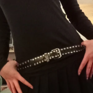 Svart nitat bälte y2k - Snyggt svart bälte med silverfärgade nitar och ett stilrent spänne. Perfekt för att ge en edgy touch till din outfit. Passar bra till både jeans och klänning.