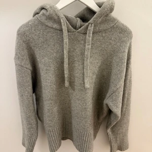 Grå stickad hoodie - Mysig grå stickad hoodie med långa ärmar och ribbade muddar. Skicket är bra. Säljer eftersom den inte används💕💕