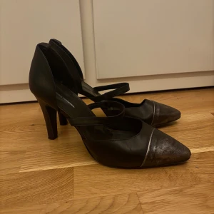 Svarta pumps med spetsig tå - Eleganta svarta pumps med spetsig tå och remmar över foten, lite slitna under sulan men inga andra defekter. Små i storlek