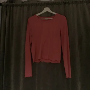 Rosa långärmad tröja - Säljer en söt rosa långärmad tröja med en croppad design. Perfekt för en avslappnad stil och kan enkelt matchas med jeans eller kjol. Tröjan har en enkel rund halsringning och är tillverkad i ett mjukt material.