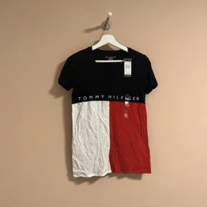 Tommy Hilfiger tröja - Helt ny T-shirt med V ringning från Tommy Hilfiger, lapparna är kvar på. Storlek XS i färgen vit, röd och marinblå! Nypris 417 kr.