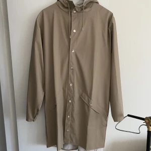 Regnjacka long - Regnjacka i en väldigt fin beige färg som tyvärr aldrig har kommit till användning. Prislappen hänger kvar🧡