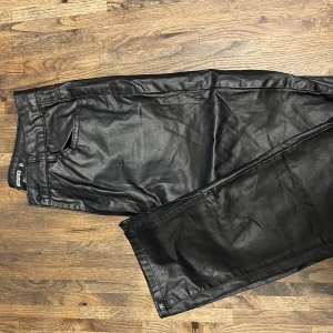 Svarta skinnbyxor  - Svarta skinnbyxor i storlek 36. Aldrig använda. Slits längst ner på benet. 