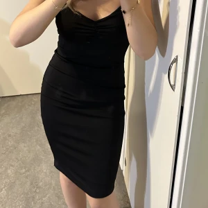 Svart enkel kläning - Svart enkel kläning med en detalj vid urringningen.  Bra skick, använd 1/2 gånger!