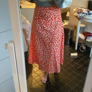 Blommig kjol - En långkjol med vita blommor på ett rött tyg. Kedja på baksidan. Inte säker på ordinariepriset men tror jag köpte den för 159 kr. Säljer den för 50 kr + frakten. Skriv till mig om ni är intresserade! 