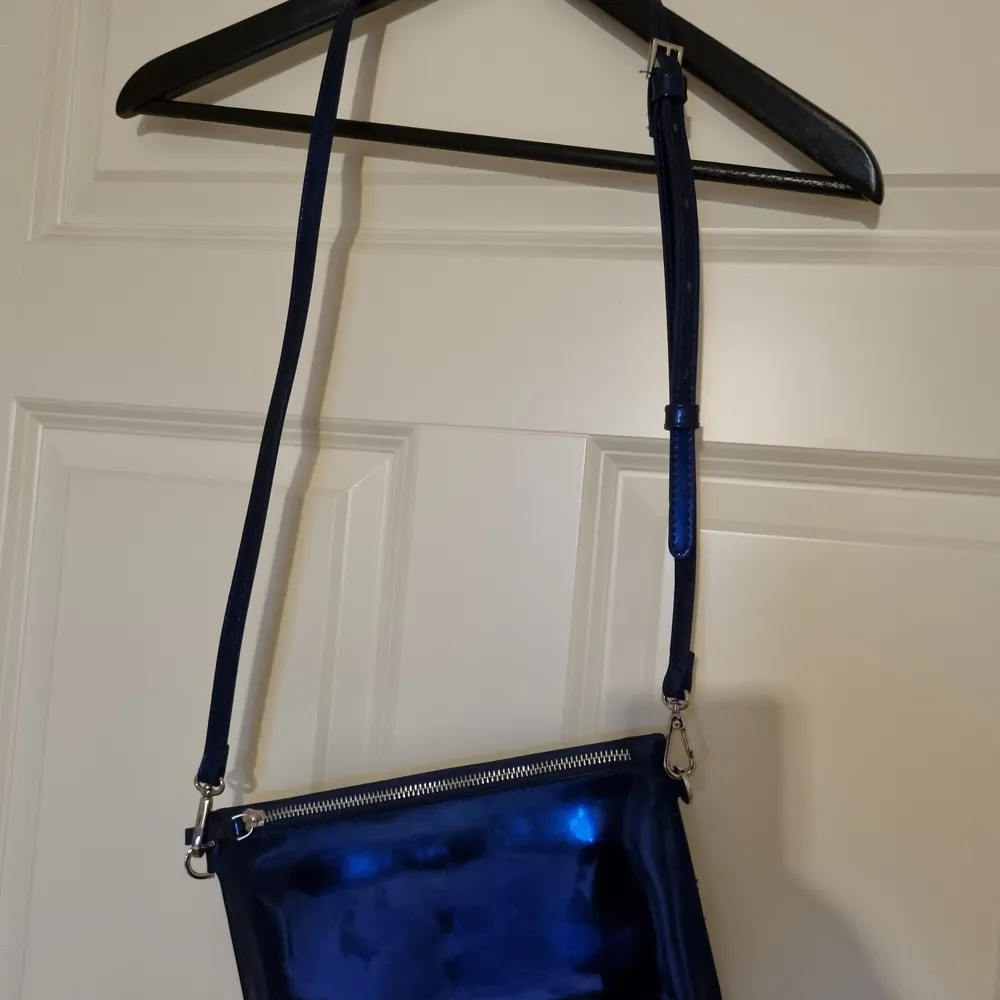 Liten blåmetallic väska från Carin Wester. Man får plats med mobil, nycklar och ett läppstift 😊. Väskor.