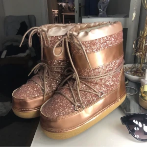 Inuikiis/Uggs liknande - Glittriga rosa, helt nyskick, passar bra på mig som har 38/39. Rymliga/stora i storleken så skulle säga att de är 38/39. Moonbootsliknande💕buda i kommentarerna
