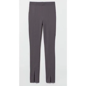 Slits byxa - Ett par leggings i stadig, ribbad trikå. De har hög midja och sytt pressveck längs benen. Slits fram vid bensluten. (Lånad bild)