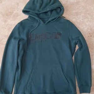 DirtCult hoodie - En snygg blågrön hoodie från Dirtcult i fint skick. Strl L, herr.