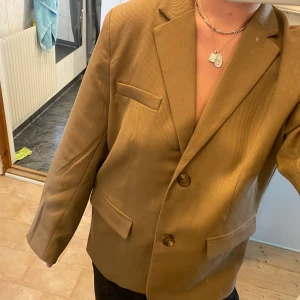 NA-KD kavaj - Helt oanvänd brun/beige kavaj från NA-KD med prislapp kvar. Köptes för 799! Hann dock klippa bort innefodret i axlarna för att slippa stora puffiga axlar innan jag insåg att det var fel storlek för mig. Men ingenting som syns eller störs på. 