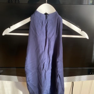 Body med öppen rygg - Marinblå body med öppen rygg och knytning i halsen. Köparen står för frakten.