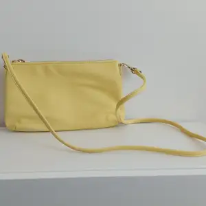 Mindre gul axelremsväska med avtagbart band från H&M. Ett fack på insidan. Priset är exklusive fraktavgift. 