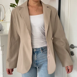 Beige kavaj från NAKD - En cool kavaj från NAKD i oversized modell. Puffiga ärmar och axelvaddar. Storleken är 38 och jag är 178cm lång. Aldrig använd, lapparna är kvar 