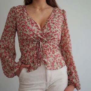 Söt blommig blus  - Söt blommig v-ringad blus med snörning framtill. Tunnt tyg och faller snyggt på kroppen. Använd ett fåtal gånger men är som ny! 