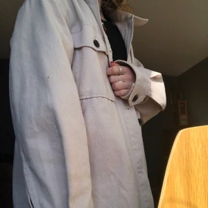 Oversized vårjacka - Superfin vårjacka från H&M. Jackans färg är en blandning av ljus grå, beige och svagt rosalila! Använd ca. 10 gånger. Säljer då passformen inte funkar för mig som är superkort. Passar säkert superfint till den som är lite längre! Jackan är i storlek XS men passar nog även för den som vanligtvis har S, den är oversized i modellen. Passar perfekt nu när våren gör sig påmind!