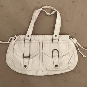 Rosa axelväska  - Rosa axelväska i fake skinn. Den är använd och som man ser på bilden så har skinnet skavts av lite. 