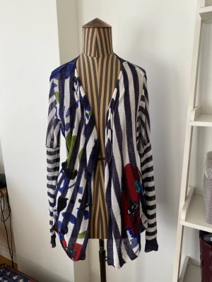 Kofta från Desigual - Fin kofta från Desigual. Vit och blå randig med blommor med paljetter. Lite använd.