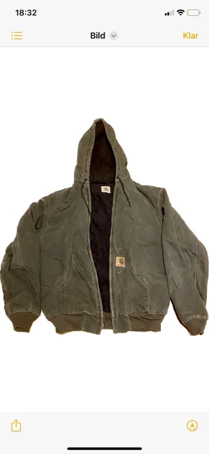 Carharrt active jacket - Militär eller olivgrön carharttjacka med luva. Inga fläckar men märket är lite slitet i vintage skick.  Mått; Bredd (55), Längd (65), armar(58).