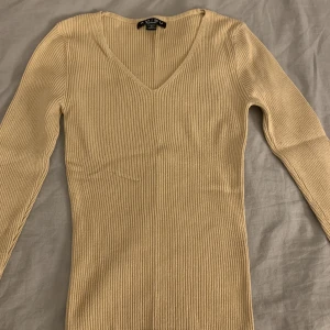 Ribbad tröja - Brun/beige ribbad tröja med V-urringning. Har stretch.