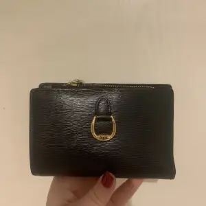 En svart äkta Ralph Lauren plånbok i svart. Detta är en lagom stor plånbok som rymmer både kontanter och kort, samt en ficka.  Köpt för cirka 1500, säljer för 500. 