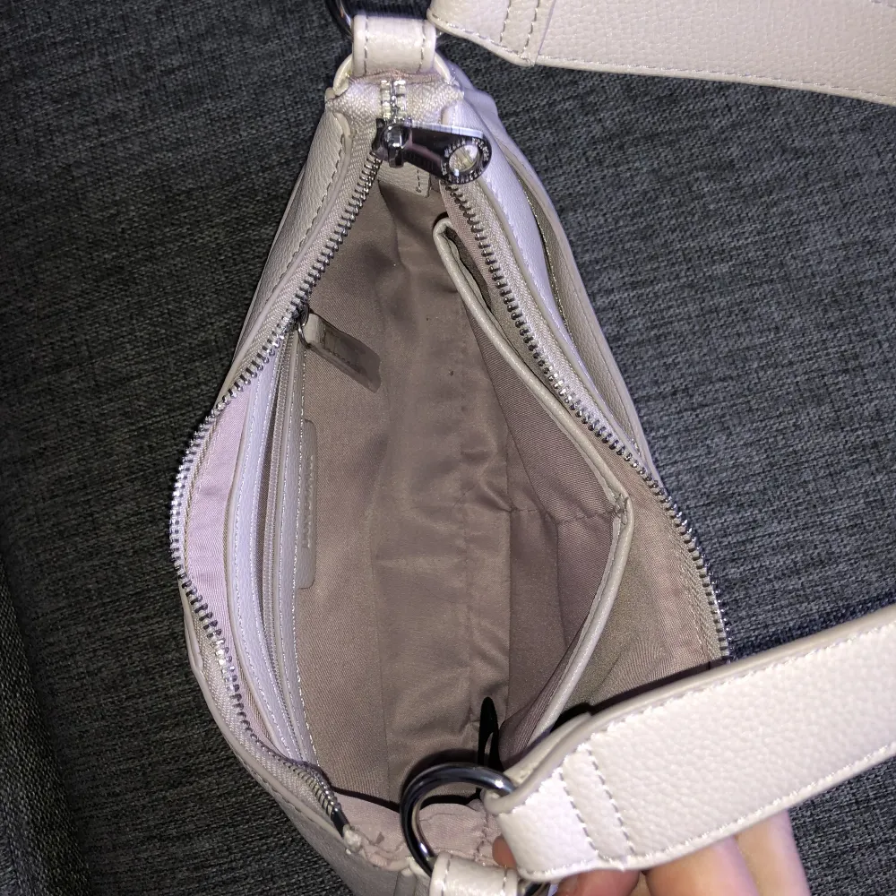 Det är en relativt liten handväska, väldigt ljuslila.  Har tre små fack i väskan, syns på bild. Aldrig använd, mått 26x17x6. Väskor.