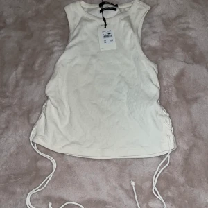 Topp - En vit topp från Bikbok med snören på sidan! Oanvänd och lappen kvar