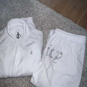 Vitt juicy couture velour sett - Säljer mitt vita sett från juicy couture. Har endast använt de 3 gånger och det är smuts längst ner på hälarna baktill då dom är väldigt långa (går att korta av) Settet säljs inte längre då det utgått, köpa på JD sports för ca 1700kr, OBS: byxorna är M