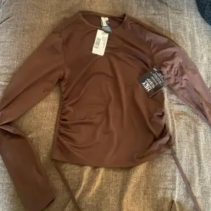 Helt ny oanvänd tröja som knyts i ryggen 😍 med alla lappar kvar!!. Köpte för ungefär 250kr.  Den är i en mörkbrun färg (mörkare i verkligheten än på bild)  och i så himla skönt material.