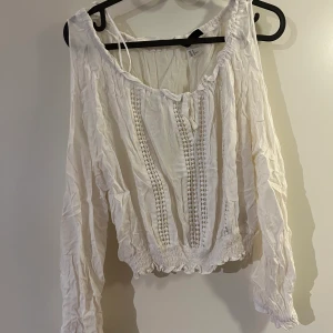 Vit topp - Blus från HM. Långärmad tröja med resår nedtill, och med öppna ärmar. Bra skick!