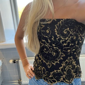 Festtopp - Så himla fin strapless festtopp i svart med guldiga detaljer. Älskar denna men den har blivit för liten för mig, (stl 38 men är lite mindre i storleken!!). 