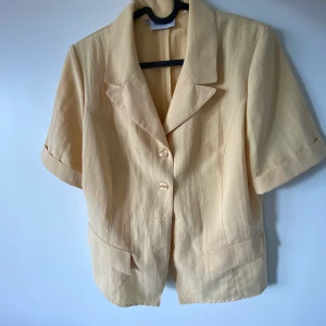 Gul vintage topp - Gul topp köpt secondhand men i bra skick! Som en kortärmad skjorta med axelvaddar.