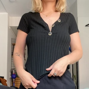 Svart topp - Topp med knappar som är snygg både knäppta och uppknäppta. Smalare ärmar. Väldigt sparsamt använd.