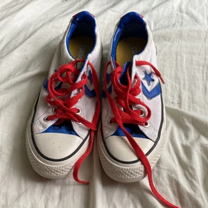 Låga converse i vitt  - Låga vita  converse med röda skosnören och blåa detaljer. De har gula sulor där converse märket fortfarande är kvar då jag använt dem få gånger. Kanterna på insidan är mörkblå. 