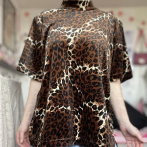 Leopardmönstrad halvpolo - Supertuff halvpolotröja i leopardmönster. Köpt second hand på Beyond retro för några år sedan. Märkt 2X, uppskattar till XL. Endast använd några få gånger av mig, fint skick! Märket är TEDDI. Frakt tillkommer. 