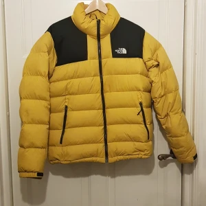 The North Face Jacka - Snygg gul north face jacka, köptde den för ca. ett år sen men har knappt använt den. I bra skick, en liten fläck i nacken av jackan som ej går bort. 