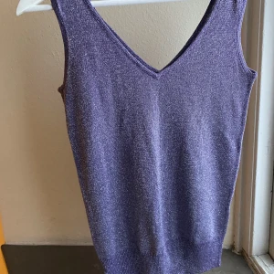 Stickat glittrigt linne/väst i lila  - Jättefint glittrigt lila linne/väst. Storlek S, på en S passar den nog lite lösare, som en väst där du kan ha en tröja under. Om du är en medium sitter den lite tightare! Märket är prohibida, spanskt 00-talsmärke ✨