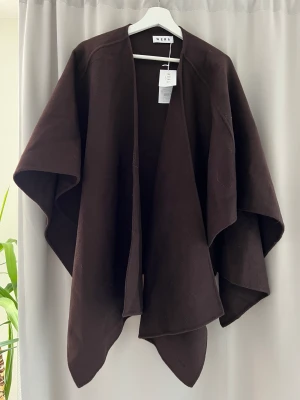 Ullcape, poncho från Wera - En ”stickad ullcape estelle” från Wera. Helt oanvänd pga flytt till Spanien och denna helt enkelt bara legat hemma. Jättefin, inköpt förra vintern. Helt osnvönd och prislappen är kvar. Nypris 999kr. 