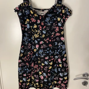 Klänning - En kort blommig klänning från hm i storlek M. Stretchiga material och figurnära passform.