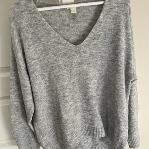 Grå stickad tröja - Stickad tröja i från hm, med en lite bredare v-ringning, perfekt för att ha lite längre ner på ena axeln. Endast använd fåtal gånger💕supermjuk och sticks absolut inte☺️Storlek S men passar allt mellan xs-l beroende på hur man vill ha den!