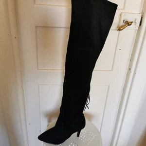 Lårhöga stövlar - Lårhöga stövlar från Nelly, endast testade. Är väl ca 6cm höjd på dem. Väldigt bekväma att använda. Snörning på baksidan och kedja på insida. 