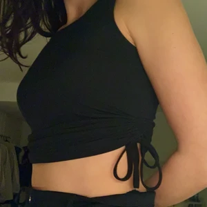 Svart linne med knytning - Knappt använd och i princip nyskick. Det finns snören på båda sidor av linnet som man kan justera hur tajt linnet sitter samt hur croppad den blir.