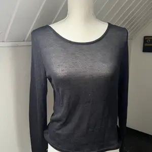 En svart långärmad tröja i ett lite genomskinligt material med en snygg öppning på ryggen. Köpt från HM i storlek M.