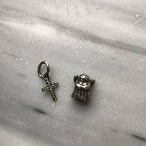 Pandora berlock & armband - Två berlocker från pandora.  Korset träs på armbandet och ängeln skruvas på. Skicket är använt men inga stora skador! Köparen står för frakten :)