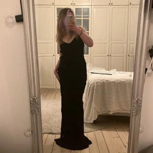 Svart långklänning  - Säljer denna otroligt fina klänning med volanger, öppen rygg och slits på ena sidan. Köpt från Mango, är endast testad med lappen kvar! Perfekt till tex. bal då den är lång och lägger sig fint på marken (jag är 165cm). Köpt för 1100kr men säljer för 900💓