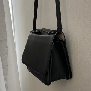 Arket Handväska - Svart handväska i läder från Arket Inre mått: 21x14x8 cm  I använt skick Spännet är magnetiskt och håller inte särskilt bra, men väskan funkar att använda ändå. :)