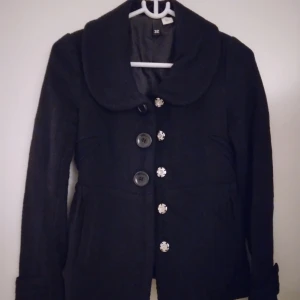 Svart jacka / tjockare kavaj. Strlk XS. Använd men brukbar än. - Svart jacka / tjockare kavaj i typ skepparkavaj-stil.  Stängs med knappar och har 2 fickor. Strlk XS.  Material: Blandade. Satinfodrad. Använd men brukbar än. FRAKT TILLKOMMER. 